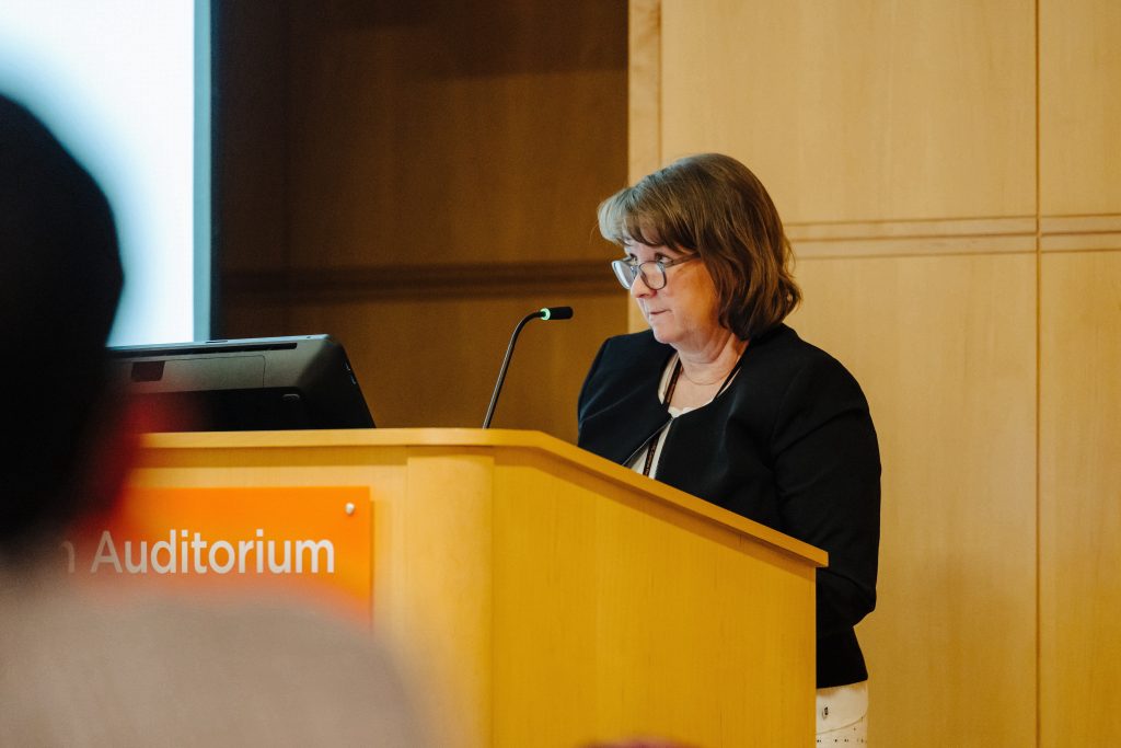 Dr. Karen Derefinko speaking at the podium at a Faculty Senate meeting