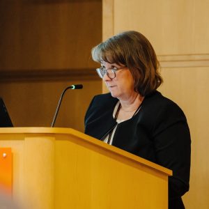 Dr. Karen Derefinko speaking at the podium at a Faculty Senate meeting