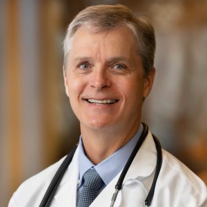 Dr. John Howington's headshot with his white coat and stethoscope on.