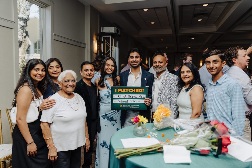 A group of people of color are posed around their student near a table, him holding his "I Matched!" sign that reads "at UT St. Thomas - Nash in Internal Medicine."