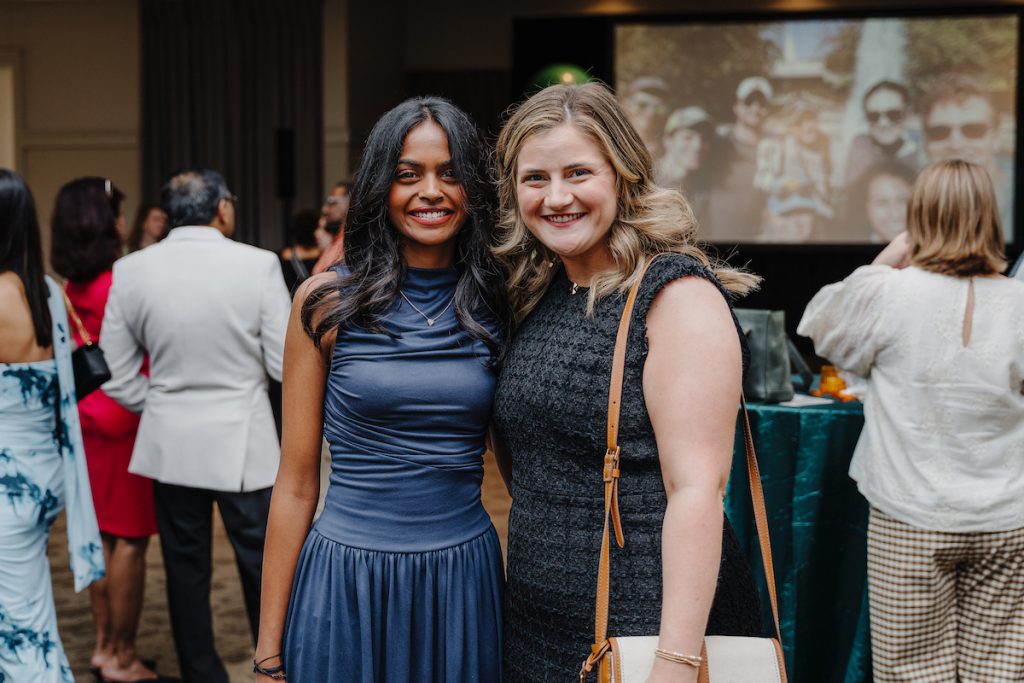 Two ladies in dresses pose for a photo.