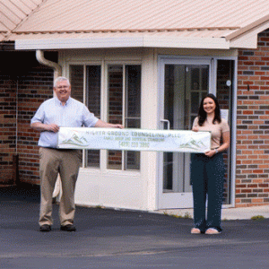 Higher Ground's director and operations manager hold a banner in front of the company