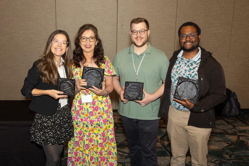 The communications and marketing team poses with the four awards.