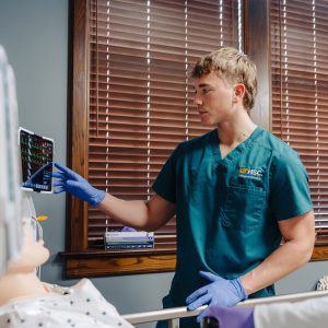 Nursing students practicing their skills on a manikin in a simulation suite.