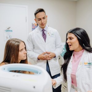 Two pharmacists in white coats speak with a patient
