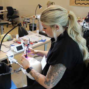 A dental program student trains at a desk with specialized equipment.
