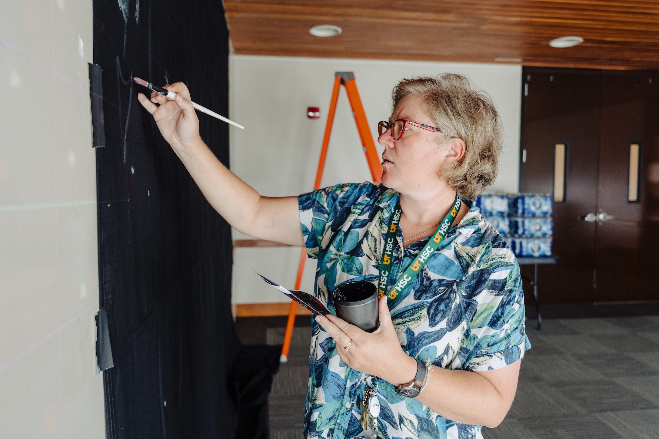 Jess Guthrie painting a canvas on a wall.