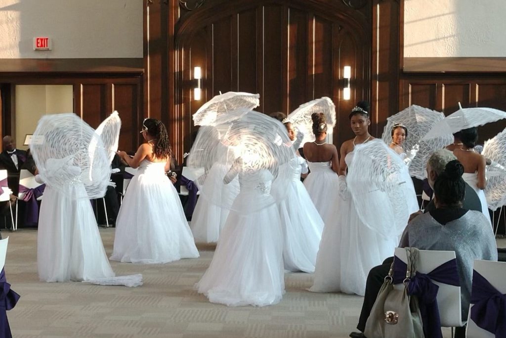 Girls in white dresses twirl with umbrellas