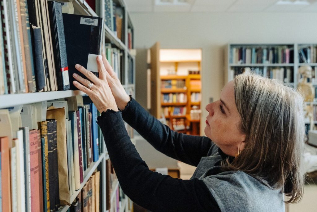 Jennifer Langford reaching for a book on a bookshelf.