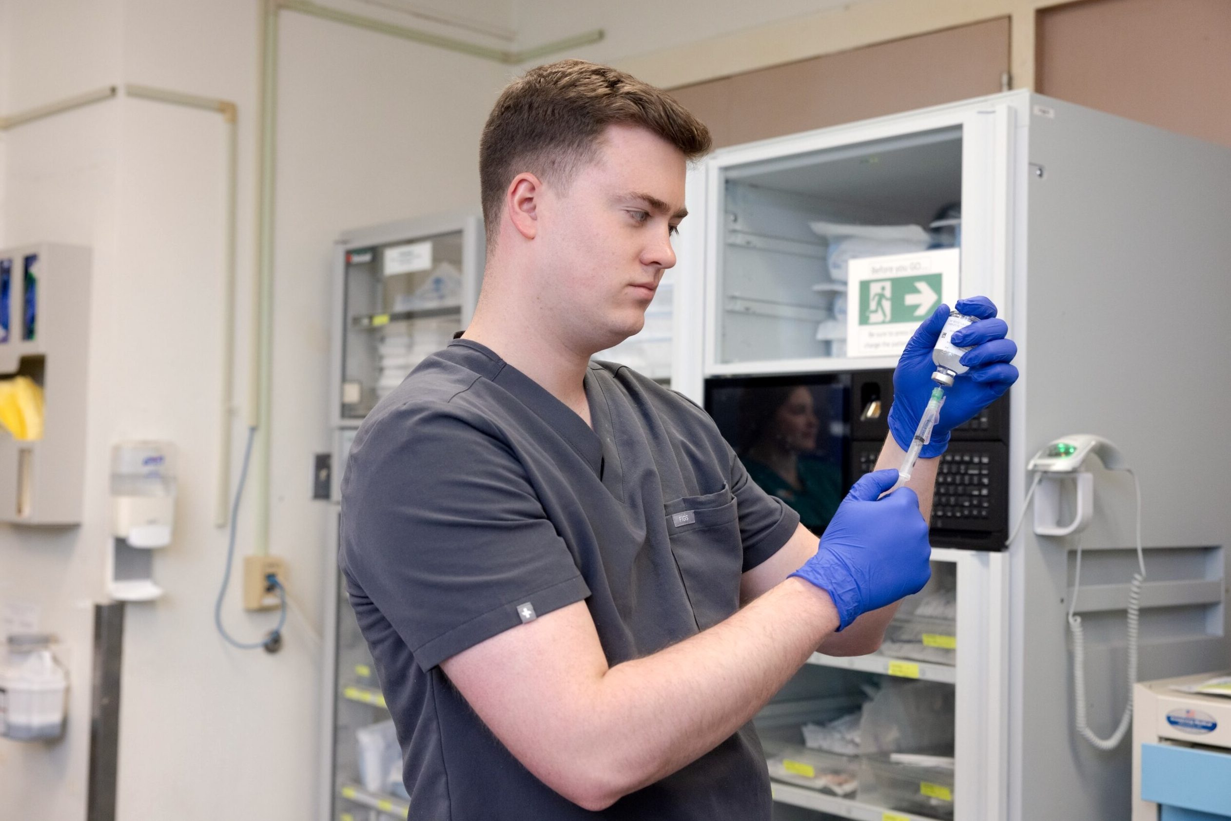 Dr. Auston Phillips draws medicine from a vial into a syringe.