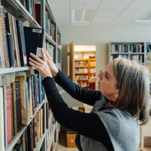 Jennifer Langford reaching for a book on a bookshelf.